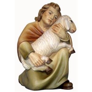 Shepherd kneeling with sheep on knee